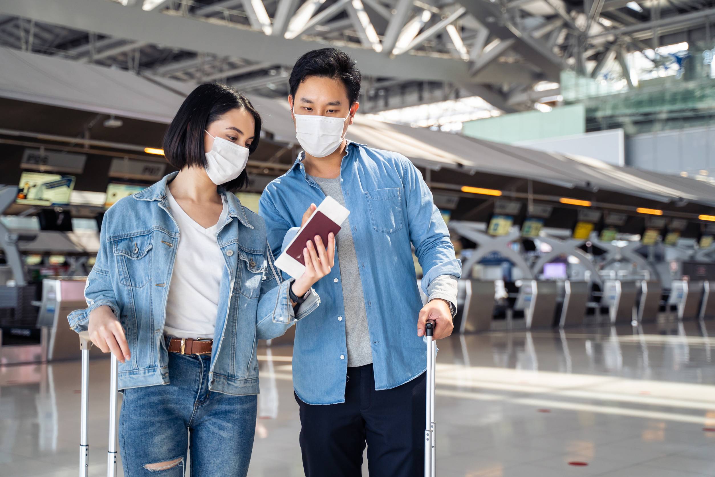 asian man and woman passengers wear face mask walk in airport terminal
